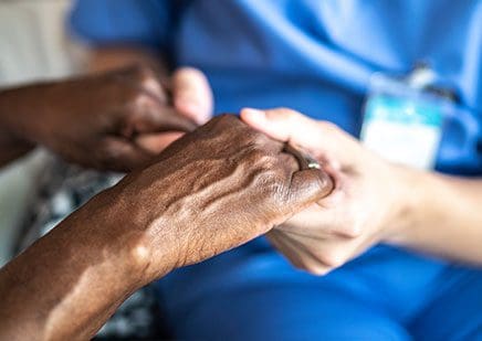 Close up of nurse holding elderly patients hands