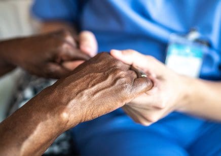Close up of nurse holding elderly patients hands