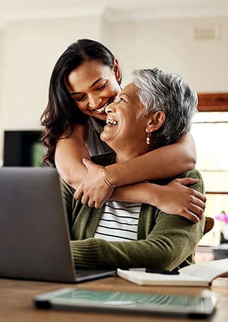 Mother and daughter smiling while using computer