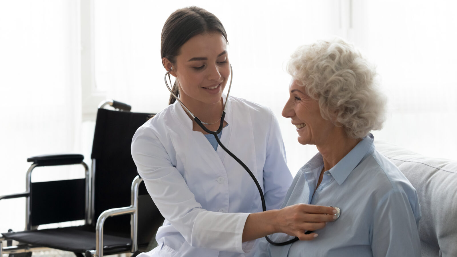 Female caregiver using stethoscope checkup of elderly senior woman patient